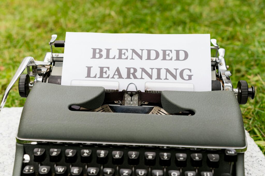 Vintage typewriter with a paper showing 'Blended Learning' text on grass.